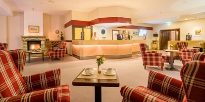 Eventlocations - Hoteleinrichtungen: Haustiere erlaubt - Calden - Lobby mit Rezeption und gemütlichen Stitzbereichen - Waldhotel Schäferberg
