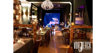 Eventlocations - Location für:: Party - Zeesen - Der Blick vom Podest zur Bühne, mit eingedeckten Tischen für einen Firmenevent. - Restaurant Vorwerck