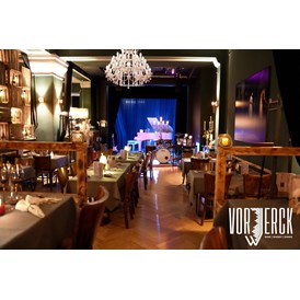 Eventlocation: Der Blick vom Podest zur Bühne, mit eingedeckten Tischen für einen Firmenevent. - Restaurant Vorwerck