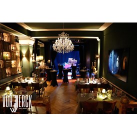 Eventlocation: Blick vom Podest zur Bühne, mit eingedeckten Tischen und Stehtischen für einen Firmenevent. - Restaurant Vorwerck