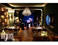 Eventlocation: Blick vom Podest zur Bühne, mit eingedeckten Tischen und Stehtischen für einen Firmenevent. - Restaurant Vorwerck